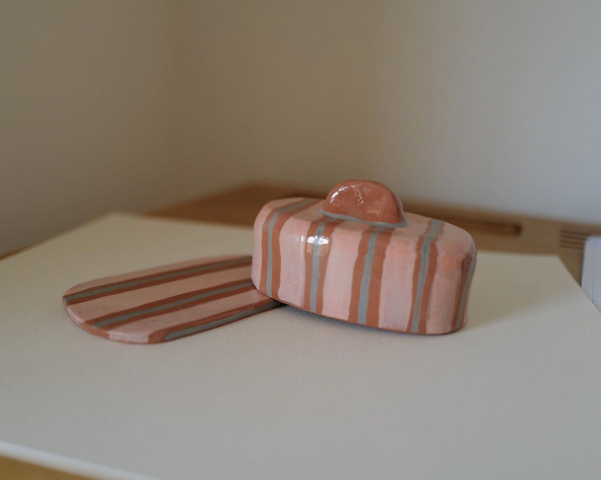 Hand-painted striped butter dish with lid beside its tray