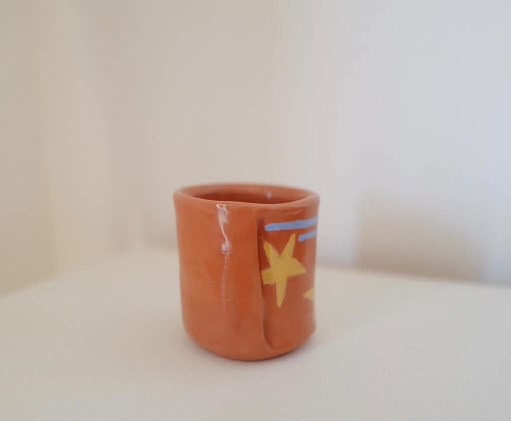 Terracotta cup with a yellow star and blue lines