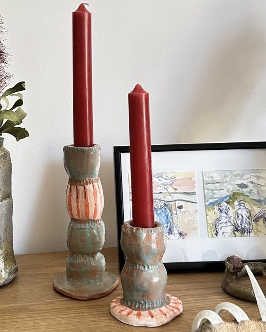 Pair of terracotta candlesticks with red candles