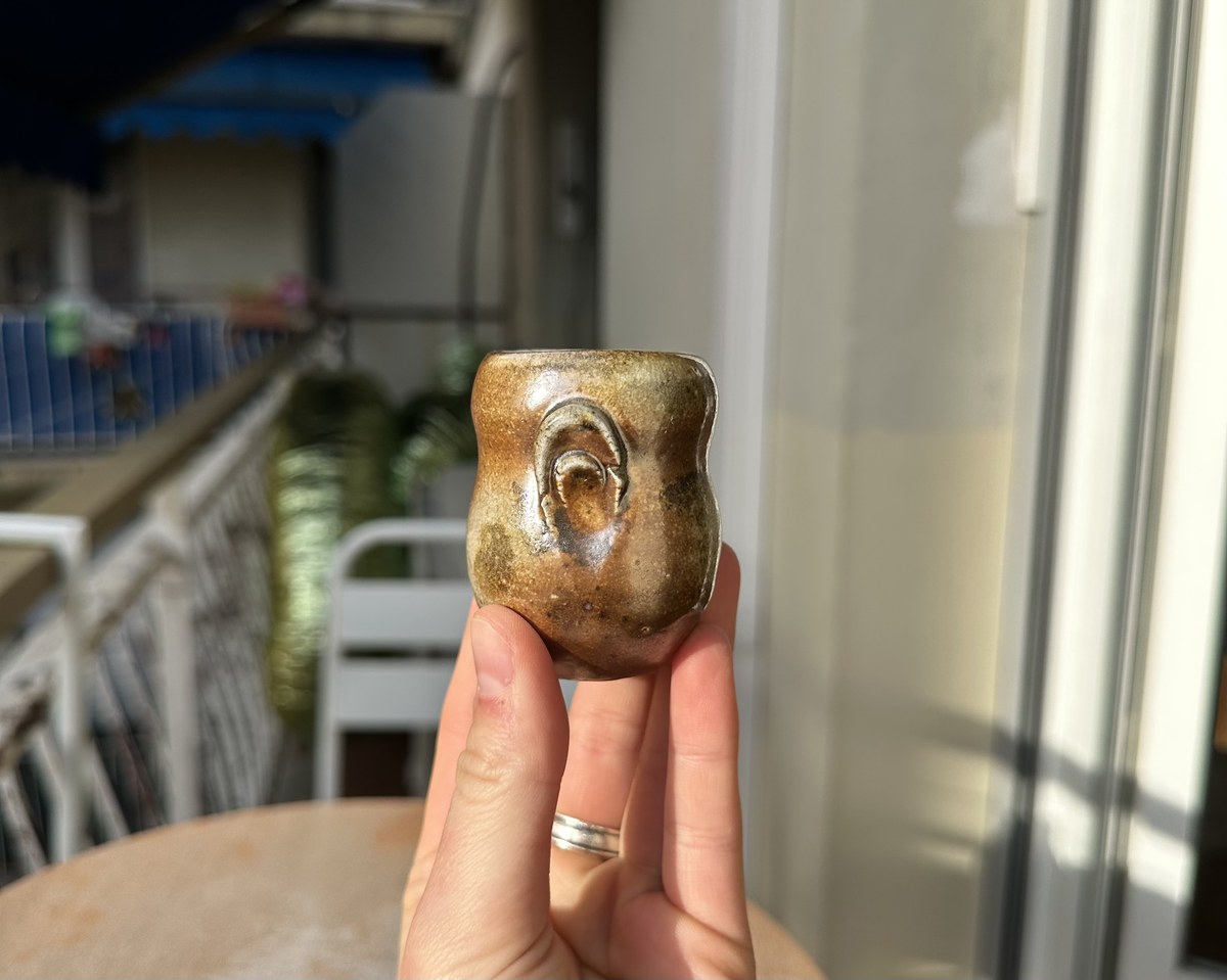 Small wood-fired cup with a stamped spiral mark
