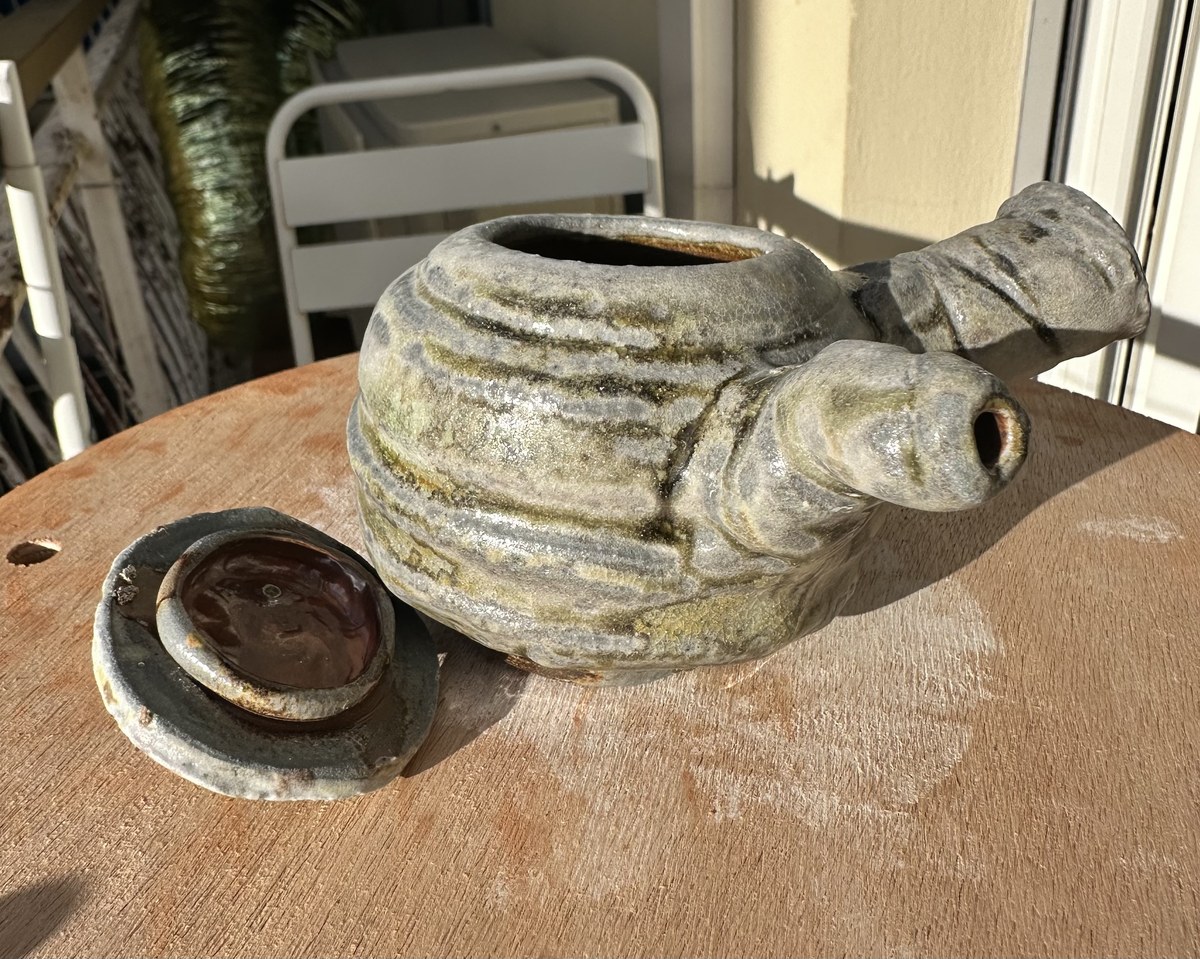 Wood-fired teapot with lid resting beside it